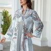 Une femme modélise une élégante abaya en perles de diamant avec broderie florale dans des tons blanc et bleu.