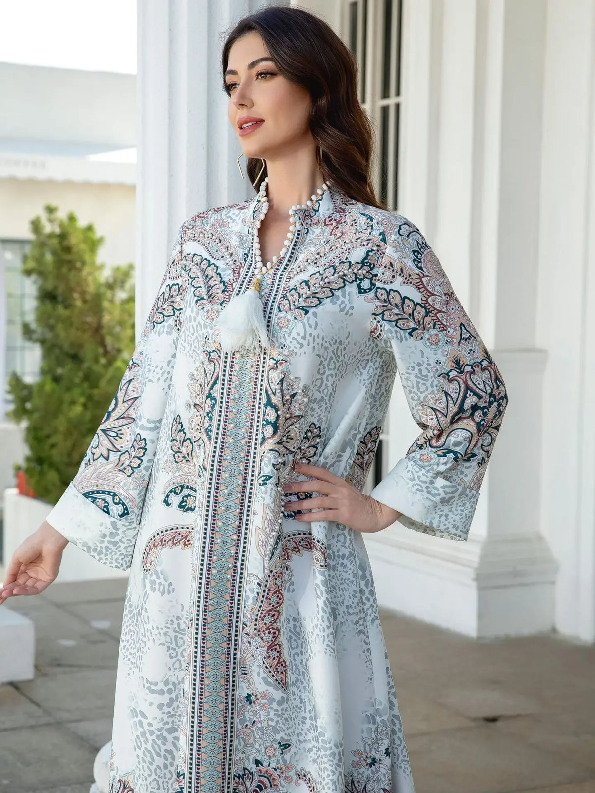 Une femme modélise une élégante abaya en perles de diamant avec broderie florale dans des tons blanc et bleu.