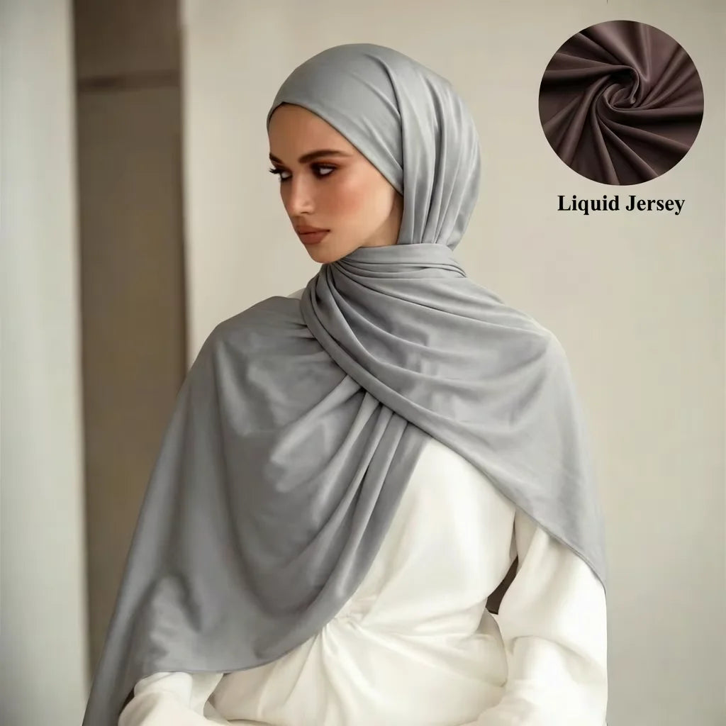Una modelo vistiendo un chal hijab de Jersey líquido gris cubriendo su cabeza y cuello.