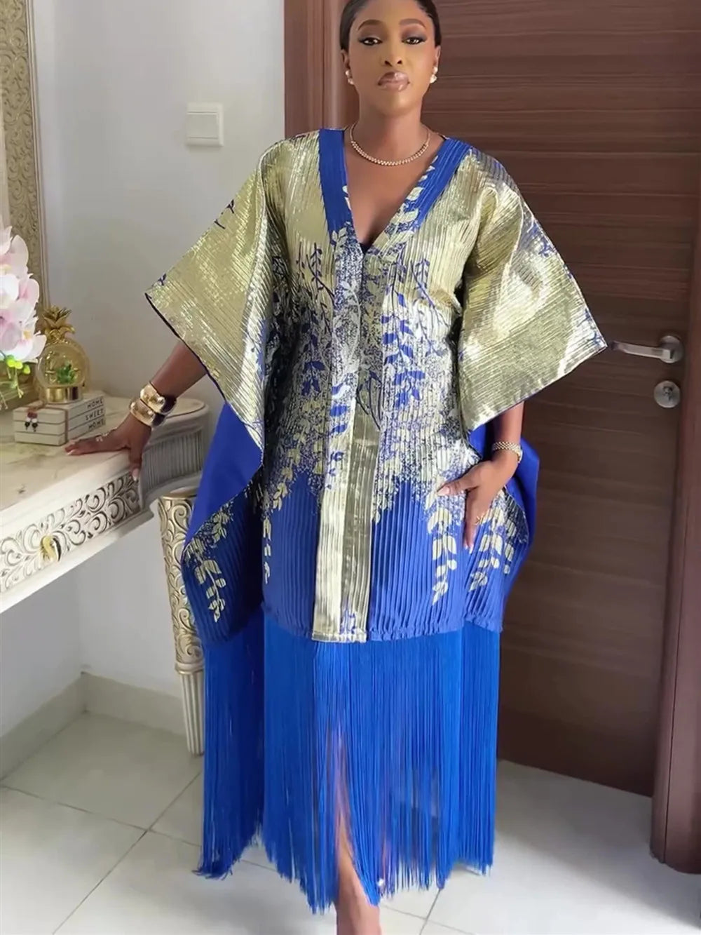 Model trägt ein traditionelles afrikanisches Dashiki Maxi-Kleid aus gold- und königsblauem Stoff mit plissierten Details.
