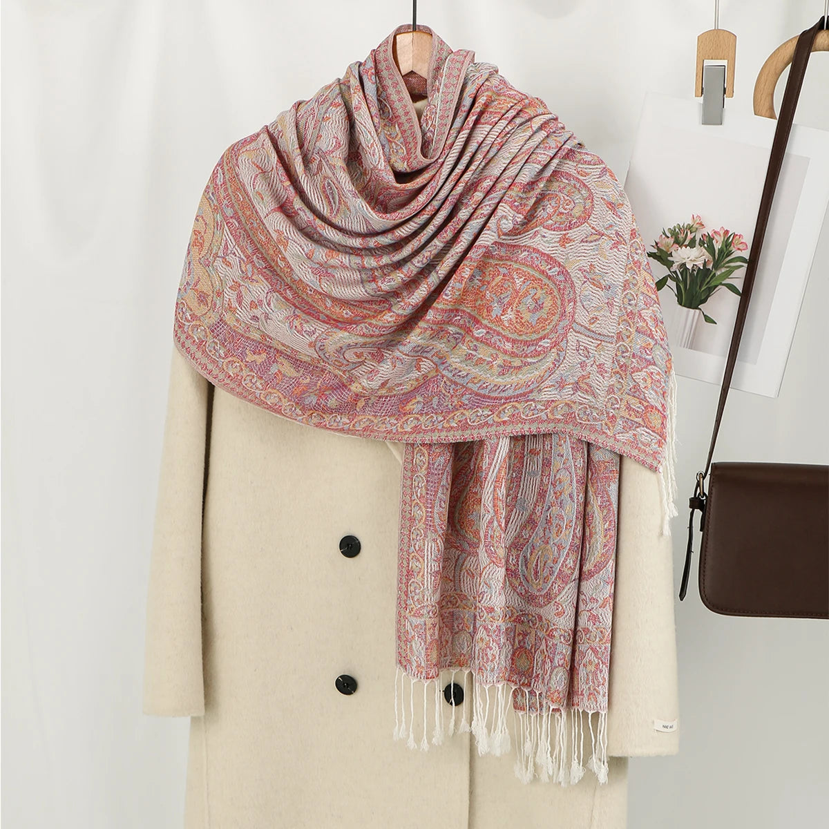 Chal vintage de bordado paisley rosa y beige drapeado sobre un blazer crema.