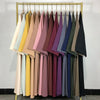 Exposition d'abayas de couleurs variées suspendues sur un présentoir doré.