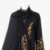 Black sheer abaya with gold floral embroidery and beaded details displayed on a mannequin.