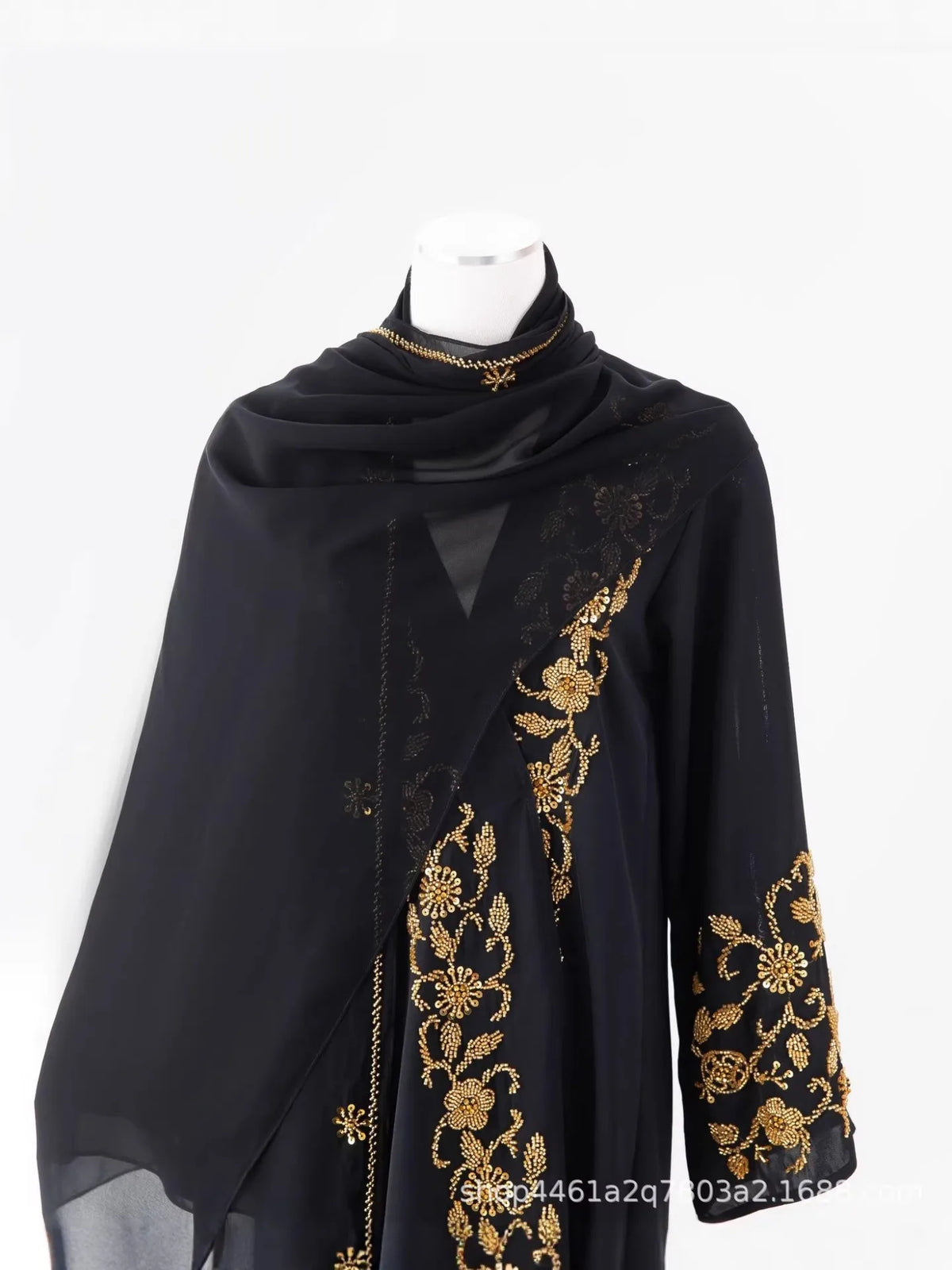 Black sheer abaya with gold floral embroidery and beaded details displayed on a mannequin.