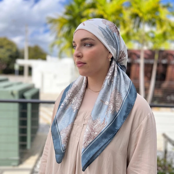 A woman wearing a satin floral print instant turban hijab in light beige and blue tones.