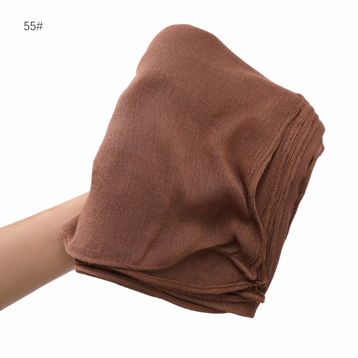 Gros plan d'un châle en crinkle de rayon marron drapé sur le bras d'une personne.