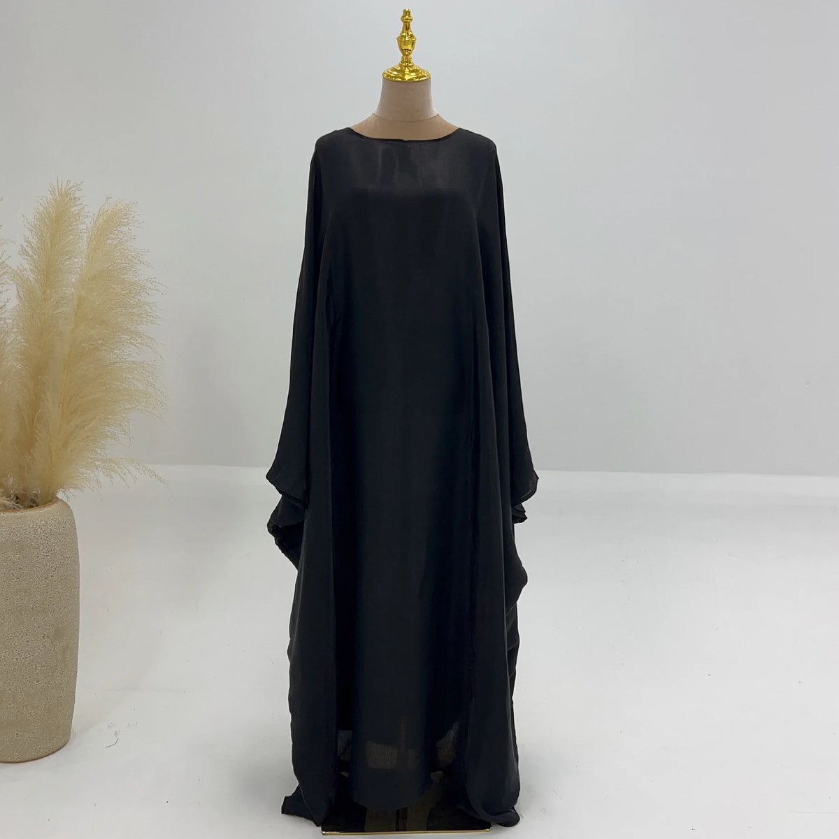 Elegante schwarze Langarm-Abaya auf einem Mannequin vor weißem Hintergrund.
