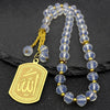 Collier avec perles de verre bleues et accents dorés, avec une étiquette dorée gravée du mot Allah