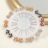 Un juego de alfileres para hijab de seda con patrones de mariposas en tonos naranja, rosa y blanco sobre una base circular bl