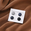 Weiße magnetische Hijab-Pins mit vier matten Magneten auf braunem Stoff.