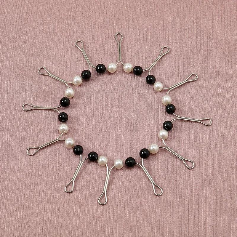 Bijou circulaire avec des perles noires et blanches alternées sur métal argenté.