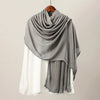 Pañuelo hijab modal gris drapeado sobre una blusa blanca, exhibido en un perchero de madera.
