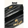 A close-up detail shot of a black crocodile pattern shoulder bag with gold hardware.