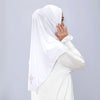 Une femme portant un hijab blanc avec broderie dorée, regardant par-dessus son épaule.