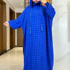 Una mujer vistiendo una abaya de algodón azul brillante con capucha y decoración floral en la cara.