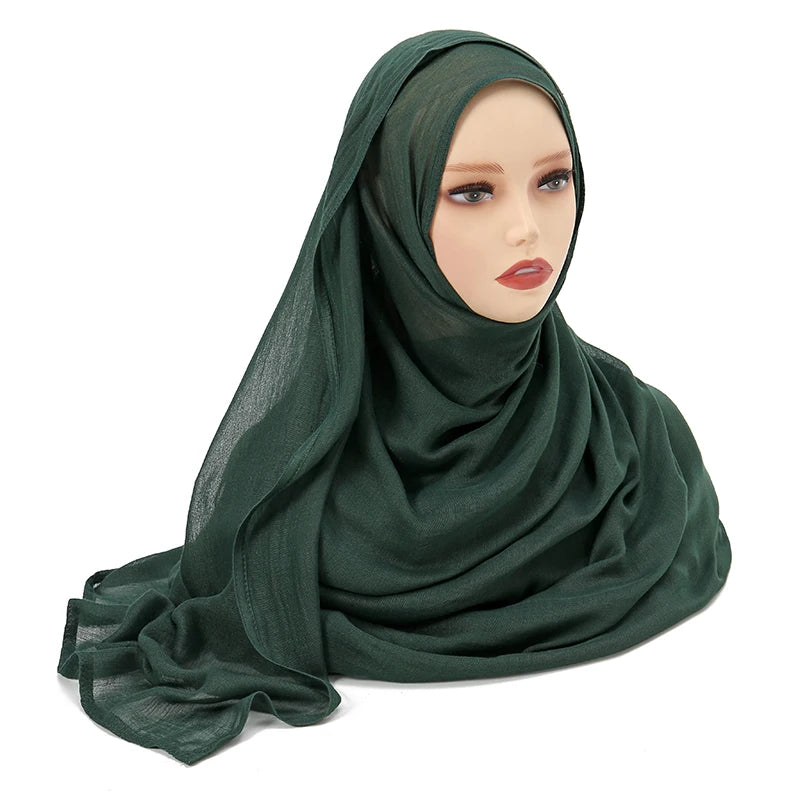 Pañuelo o chal de algodón rayón verde oscuro, drapeado sobre la cabeza y los hombros de un maniquí femenino.