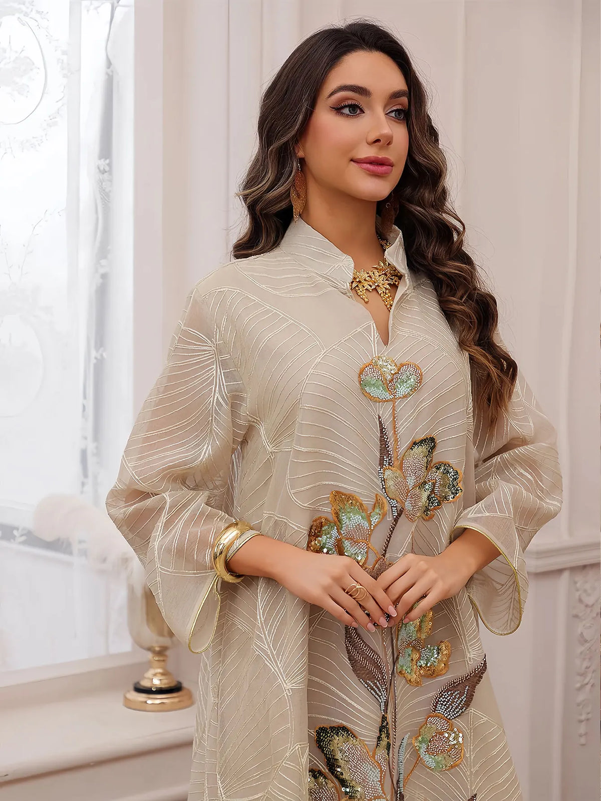 Eine Frau modelliert ein beige Abaya mit goldener Stickerei und Pailletten für Abendkleidung.