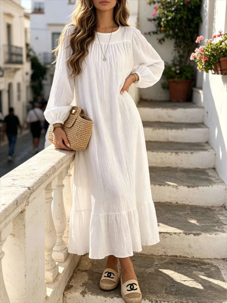 Une femme portant une longue robe bohème blanche à volants, debout sur des marches extérieures.
