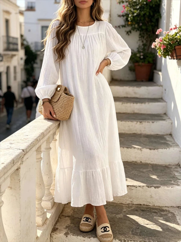 A woman wearing a white bohemian maxi dress with ruffle hem standing on outdoor steps.