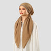 Une femme portant un bonnet et un foulard en lin beige uni assortis avec des embellissements argentés.