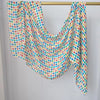 Mehrfarbiger Kopfturban mit blau-orange-grünen Polka-Punkten, über einer Kleiderstange drapiert.
