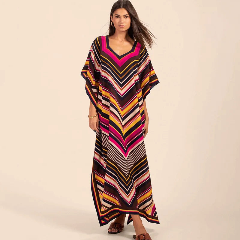 Una mujer modela un caftán largo y fluido con rayas multicolores en negro, rosa, amarillo y naranja.