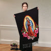 Una mujer sostiene una bufanda personalizada negra con la Virgen de Guadalupe en colores vibrantes y diseños florales.