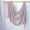 Un foulard modal de couleur beige clair drapé sur un cintre en bois.