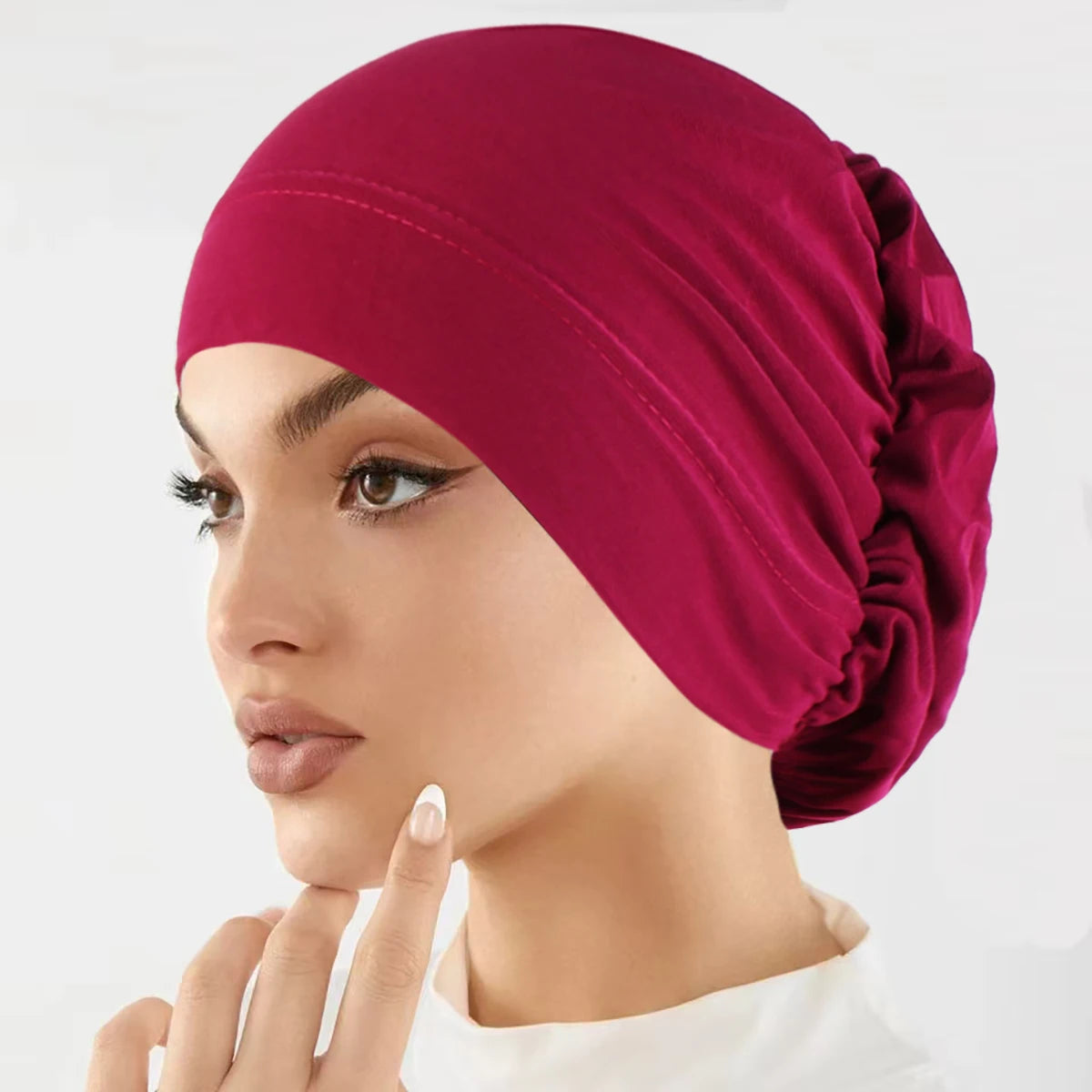 Nahaufnahme einer Frau mit einem tiefmagenta Stretch-Turbanmütze.