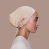 Vue de profil rapprochée d'une femme portant un bonnet inner de hijab beige à cordon.