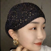 Nahaufnahme einer Frau mit einem eleganten schwarzen elastischen Turbanhut, verziert mit Gold-Strass.