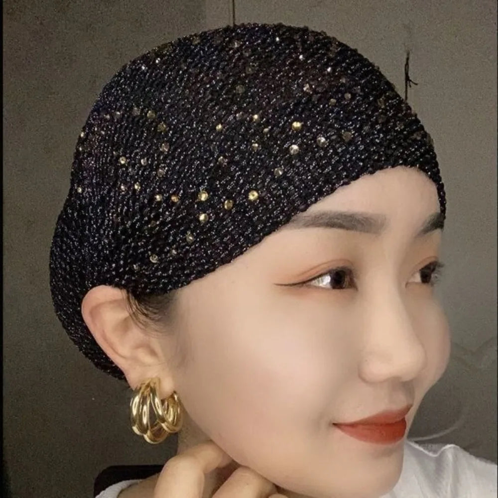 Nahaufnahme einer Frau mit einem eleganten schwarzen elastischen Turbanhut, verziert mit Gold-Strass.