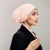 Eine Frau trägt eine zarte rosa Strass-Hijabkappe und ein schwarzes Samt-Oberteil.