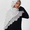 Una mujer vistiendo un hijab de punto con estampado de lunares blancos y negros.