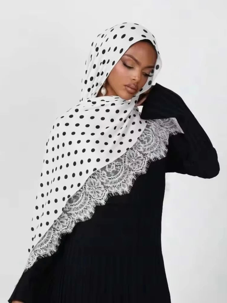 Una mujer vistiendo un hijab de punto con estampado de lunares blancos y negros.