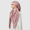 A model wearing a pink satin silk instant hijab scarf draped around her head and neck.