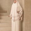 Eine Frau trägt ein beige, mehrlagiges Spitzen-Khimar-Abaya-Set mit passender Hijab vor neutralem Hintergrund.