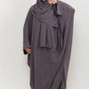 Eine Frau trägt ein traditionelles, schlichtes Abaya-Set in anthrazitgrauer Farbe mit passender Hijab.