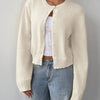 Une femme portant un pull en tricot crème sur un jean bleu clair.