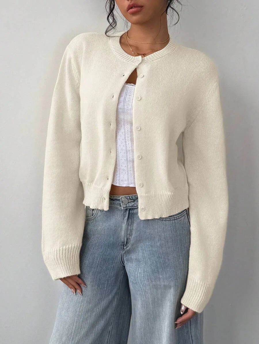 Une femme portant un pull en tricot crème sur un jean bleu clair.