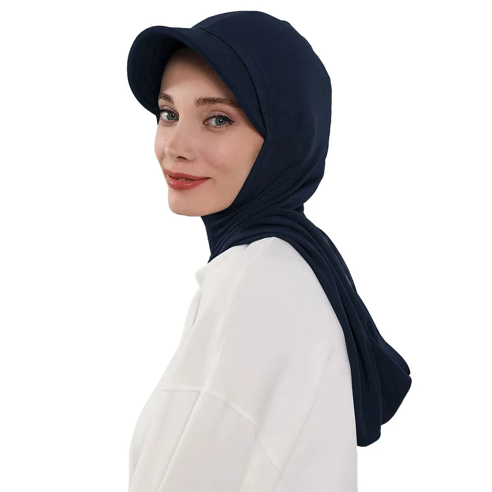 Une femme portant un bonnet hijab bleu marine couvrant et un haut blanc.