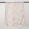 A light pink and green floral printed linen hijab scarf draped over a hanger.