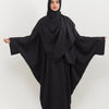 Eine Frau in einem schwarzen traditionellen, bescheidenen Abaya-Set, die nach vorne blickt.