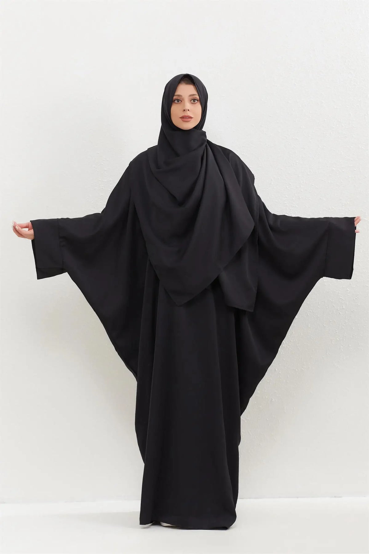 Eine Frau in einem schwarzen traditionellen, bescheidenen Abaya-Set, die nach vorne blickt.