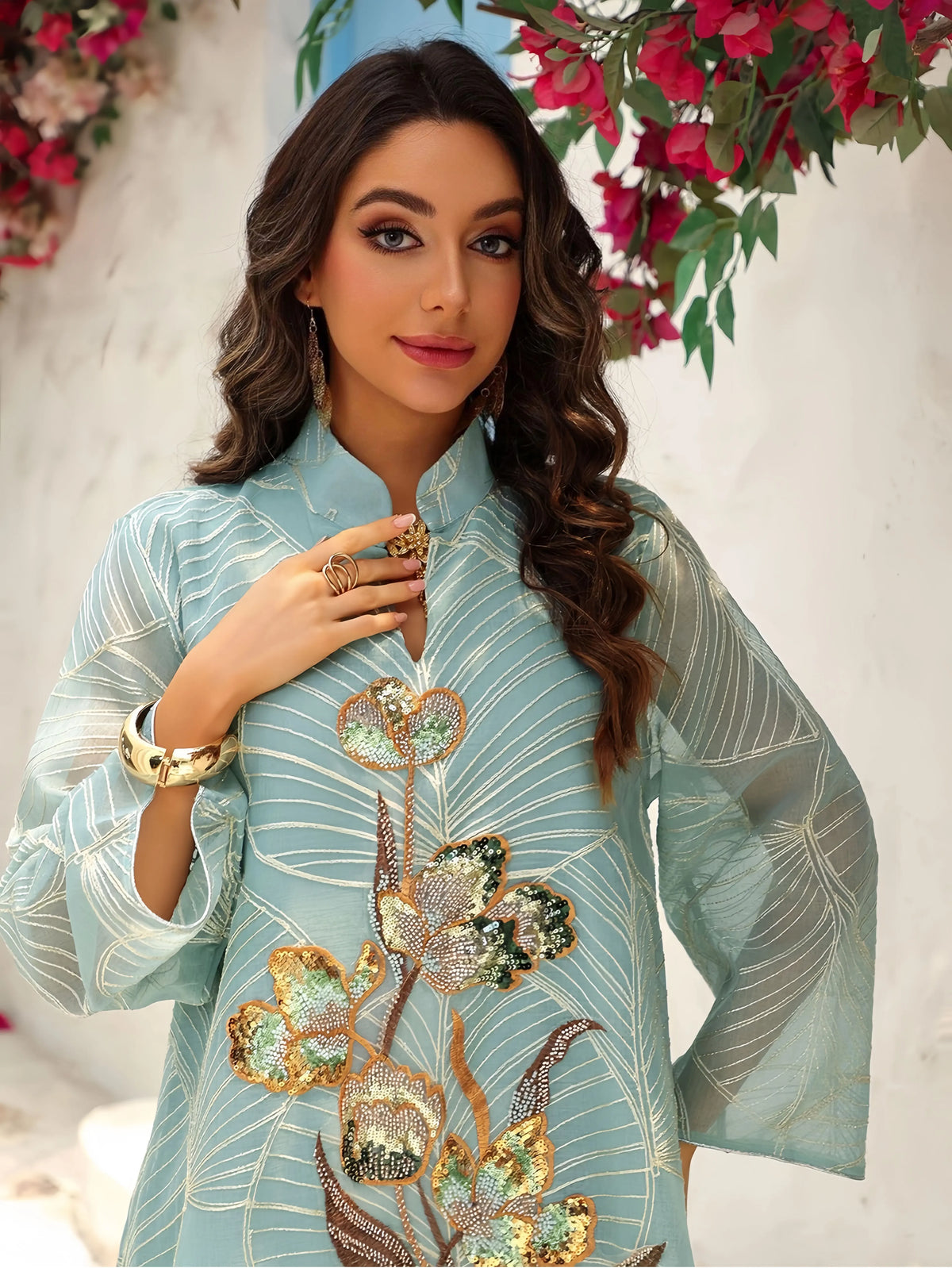 Eine Frau modelliert eine hellblaue Pailletten-bestickte Abaya mit goldenen Akzenten und durchsichtigen Ärmeln.