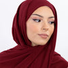 Une femme portant un hijab en mousseline marron foncé, regardant sur le côté.