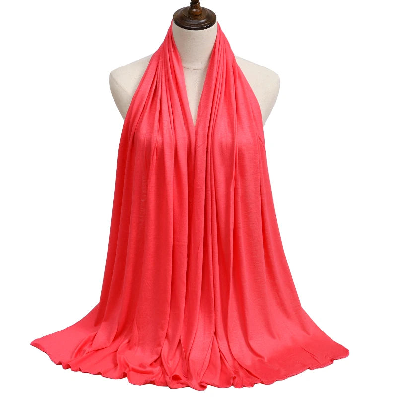 A vibrant coral pink premium modal jersey hijab draped around a mannequin's neck.