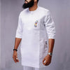 Un homme portant un costume de mariage musulman traditionnel africain blanc avec broderies dorées sur la poche de poitrine.