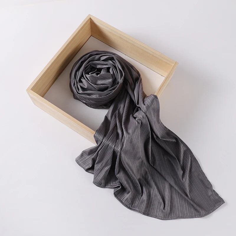 A dark gray ribbed jersey hijab scarf is draped within a light wooden frame.