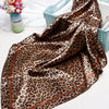 A luxurious brown leopard print silk satin scarf draped over a light blue tray.